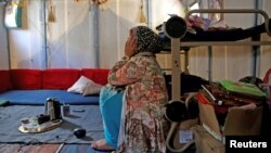 FILE - Syrian refugee Walaa, 26, sits inside her family's tent at the Souda municipality-run camp on the island of Chios, Greece, Sept. 7, 2016. 