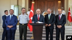 Turkey's Prime Minister Binali Yildirim, center, Chief of Staff Gen. Hulusi Akar, center left, Justice Minister Bekir Bozdag, left, Interior Minister Efkan Ala, second right, and Defense Minister Fikri Isik attend a press conference in Ankara, Turkey, Sat